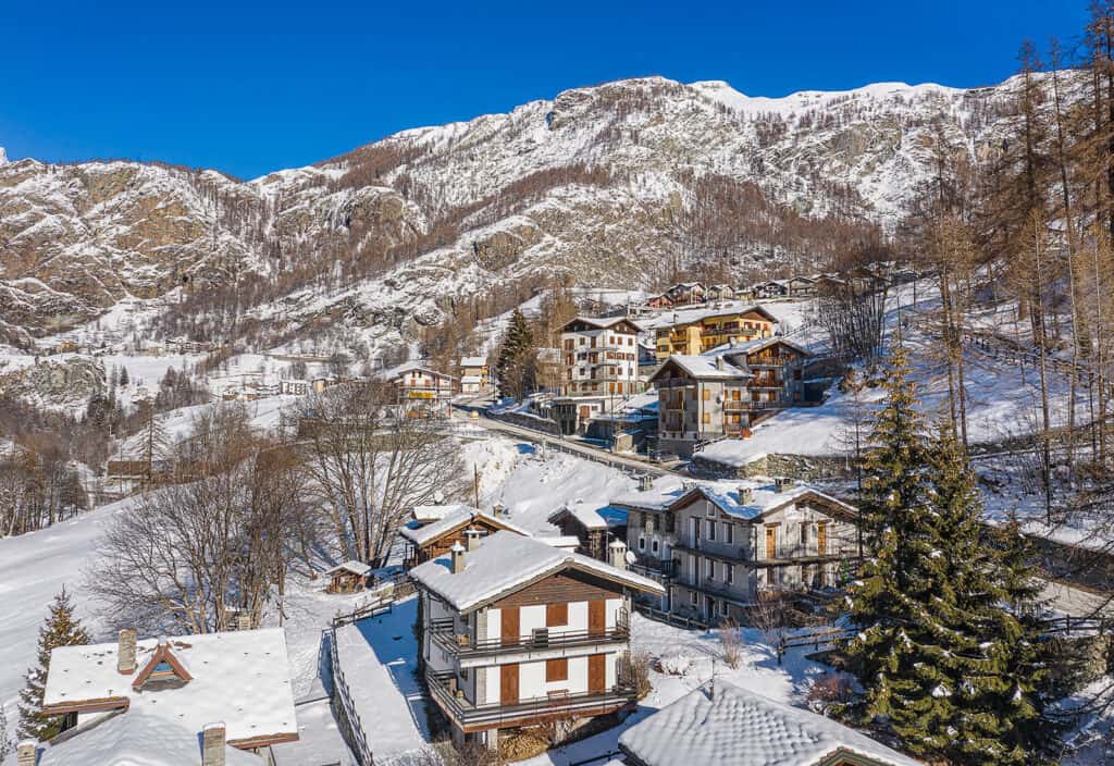 Case in pietra del villaggio innevato di Valtournenche tra gli abeti